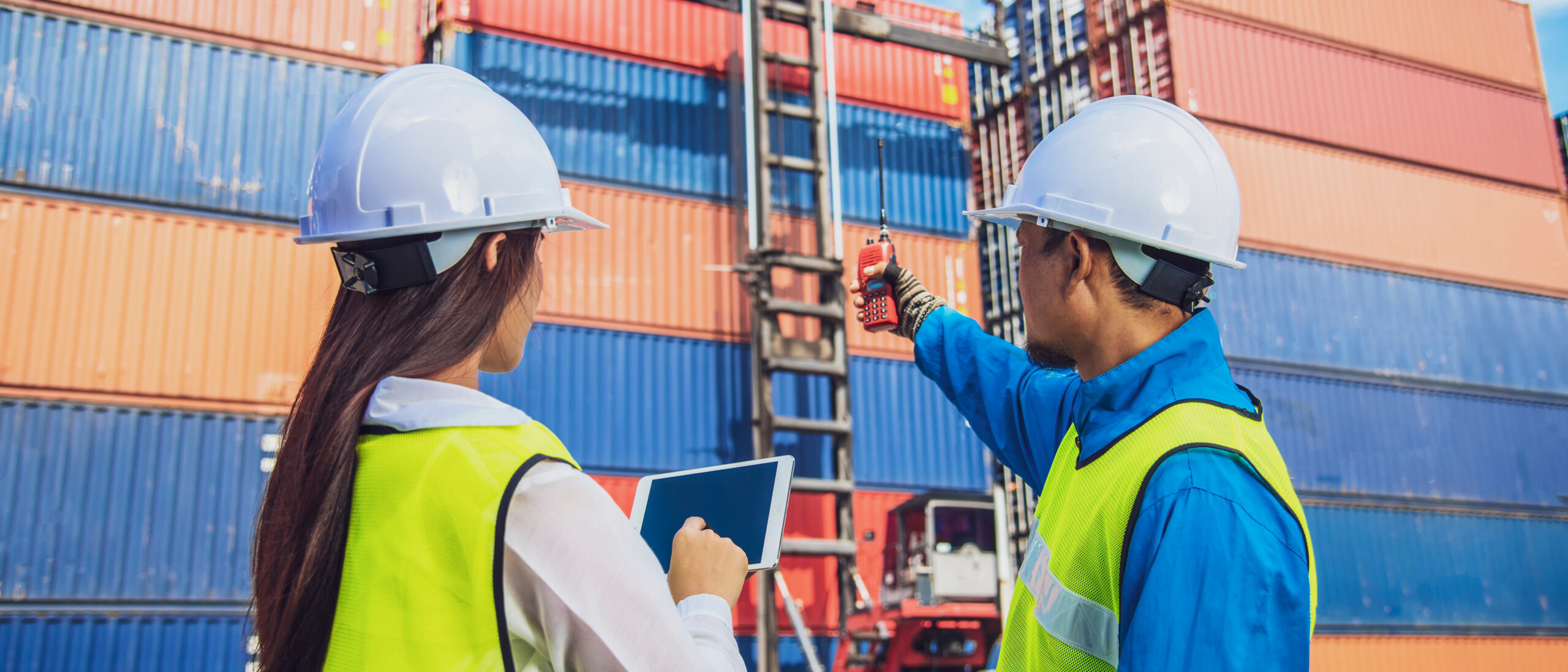Banner photo of Conceptual image of logistics business, Engineer with Forklift truck lifting cargo container box in logistic industrial area Immagine di un'area portuale con operatori al lavoro con tablet